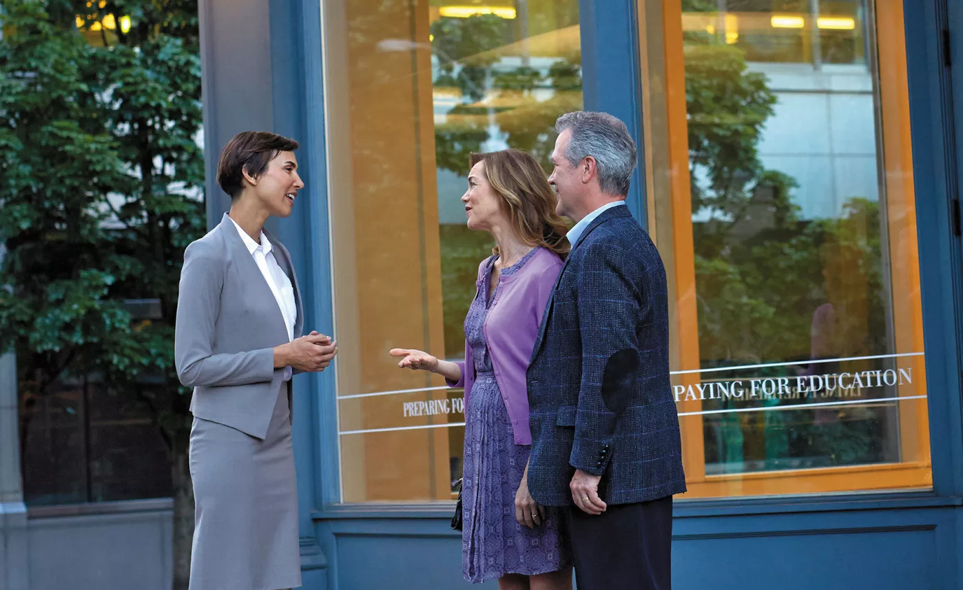  Un représentant en services financiers rencontre deux clients à l’extérieur d’un immeuble bleu.
